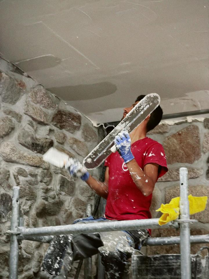 Operario de Construfuerte enluciendo el techo de una casa de piedra — obra de Construfuerte