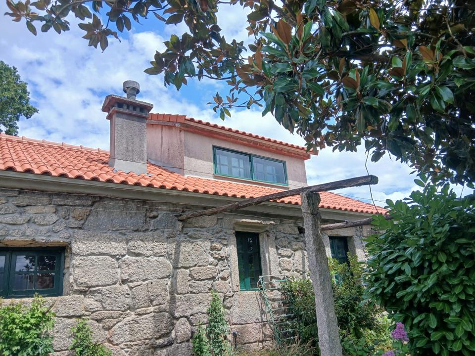 Tejado de teja y chimenea renovados en una casa de piedra — obra de Construfuerte